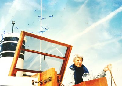 Low angle view of smiling woman standing against sky