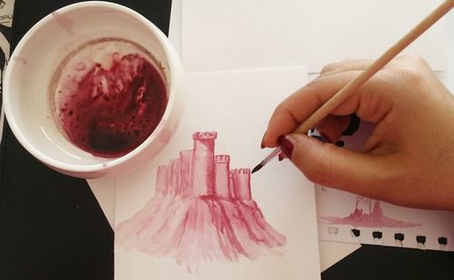 Close-up of hand holding coffee cup on table