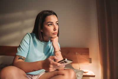 Side view of young woman using mobile phone at home