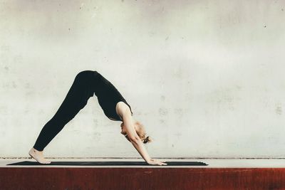 Low section of woman with arms raised against wall