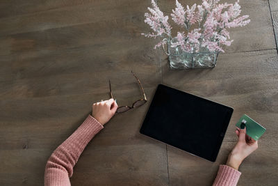 High angle view of woman hands holding credit card on table