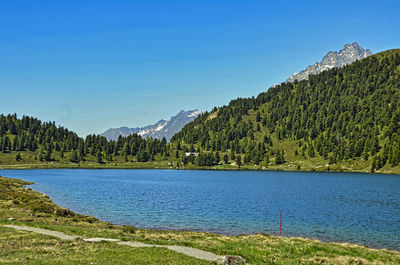 Scenic view of lake and mountains against blue sky