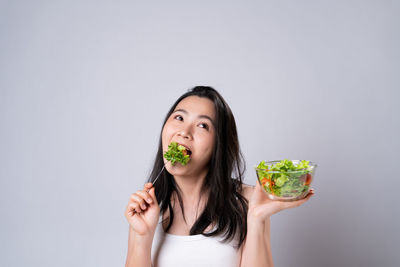 Portrait of woman eating food against white background