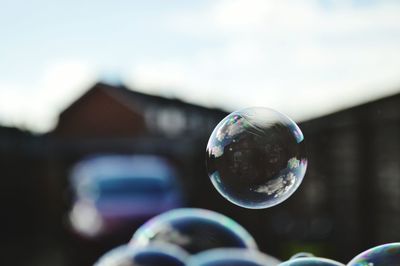 Close-up of bubbles with house and car in background