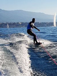 Full length of man surfing in sea against clear sky