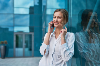 Portrait of smiling businesswoman standing by glass outdoors