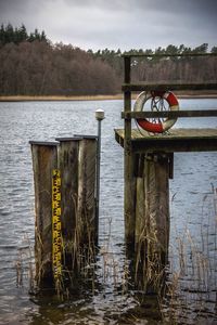 Life belt on pier over river against sky