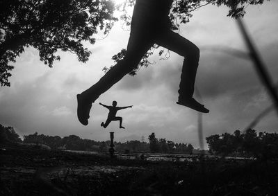 Low angle view of boys jumping against sky