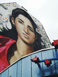 Low angle portrait of young woman against sky