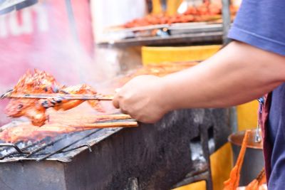 Close-up of person preparing food on barbecue grill