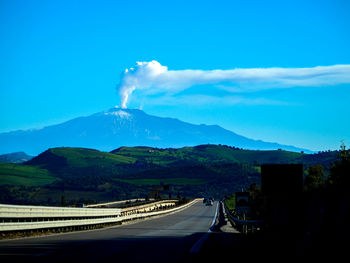 Panoramic view of road and mountains against blue sky