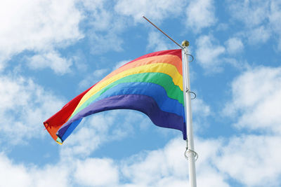 Low angle view of rainbow flag against cloudy sky