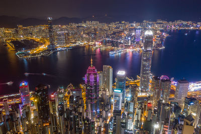 River amidst illuminated cityscape against sky at night