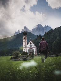 Rear view of man walking towards church on land