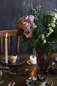 The beautiful festive table with rustic bouquet, cupcakes and candles