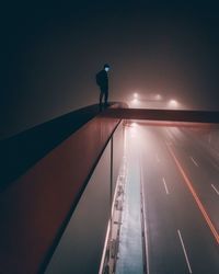 Silhouette man on illuminated road against sky at night