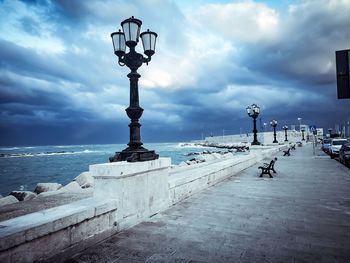 View of street light by sea against cloudy sky