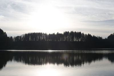 Silhouette trees by lake against sky during sunset