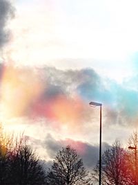 Low angle view of bare trees against cloudy sky