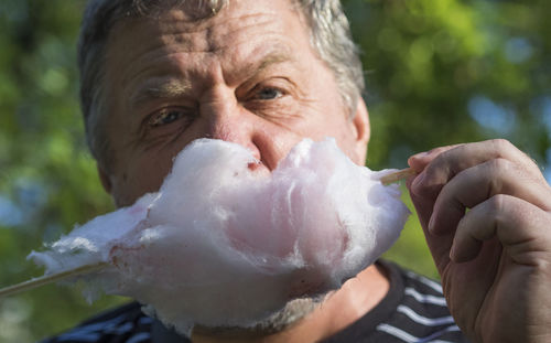 Close-up of senior man eating cotton candy