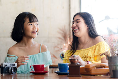 Smiling friends sitting on table in cafe