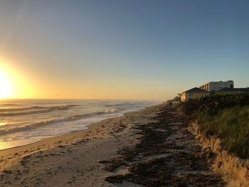 Scenic view of beach against clear sky during sunset