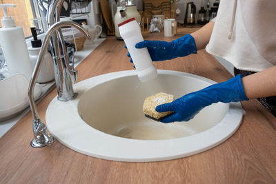 Midsection of woman washing hands in sink