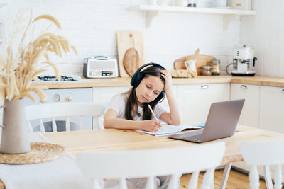 Girl writing homework on table at home