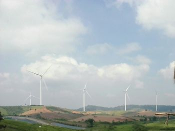Wind turbines on field against sky