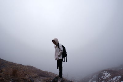 Side view of man standing on mountain against foggy smoky sky