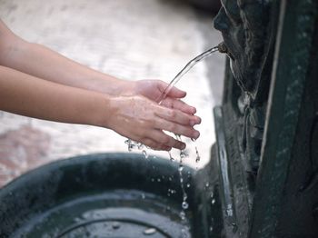 Wash your hands under  water of an old fountain