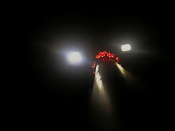 Low angle view of illuminated lamp against black background