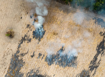 Aerial view of agriculture farm with smoke from crop fire burning releases carbon dioxide. 