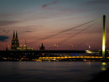 Illuminated bridge over river against sky at night