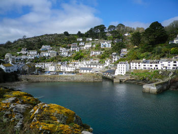 High angle view of buildings by sea against cloudy sky