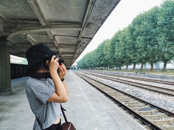 Side view of young woman standing on railroad track