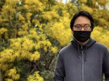 Portrait of young man standing against plants