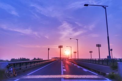 Illuminated road against sky at sunset