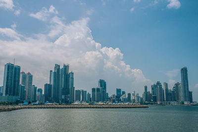 City at waterfront against cloudy sky