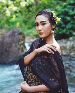 Portrait of beautiful young woman standing on rock