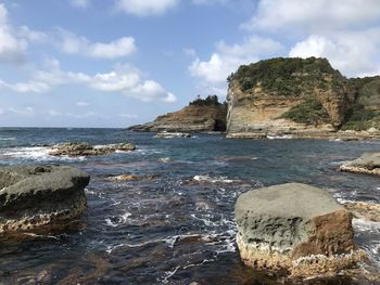 Rock formations on shore against sky