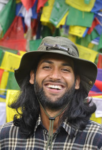 Closeup of a happy long haired young man looking at camera, posing against tibetan prayer flags