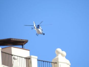 Low angle view of airplane flying against clear blue sky