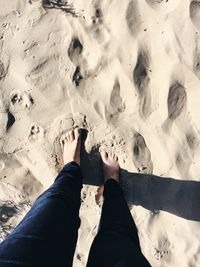 Low section of woman standing on sand at beach