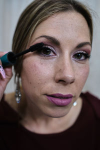 Young woman puts on makeup in the bathroom while looking in the mirror