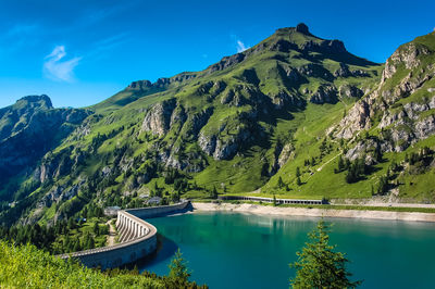 Scenic view of dam and mountains against blue sky