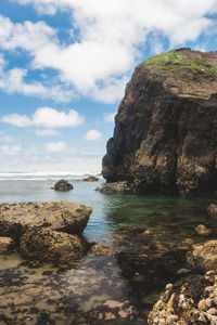 Rock formation on sea shore against sky