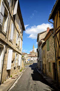 Empty road amidst buildings against sky