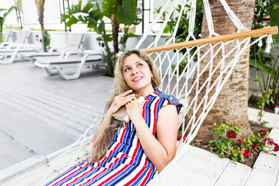 Portrait of smiling young woman standing against plants