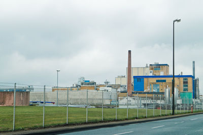 Road by buildings against sky